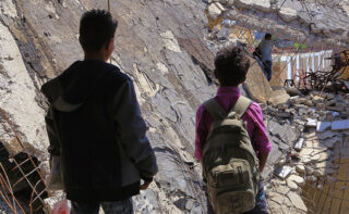 two boys standing in rubble in yemen