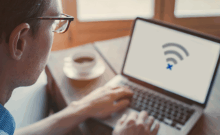 Person sitting at desk with no internet symbol on computer screen