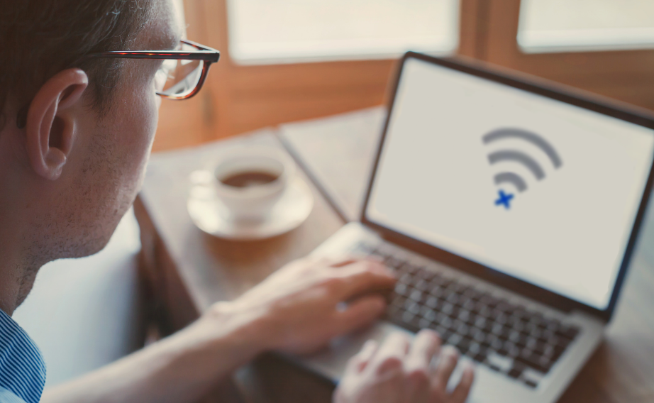 Person sitting at desk with no internet symbol on computer screen