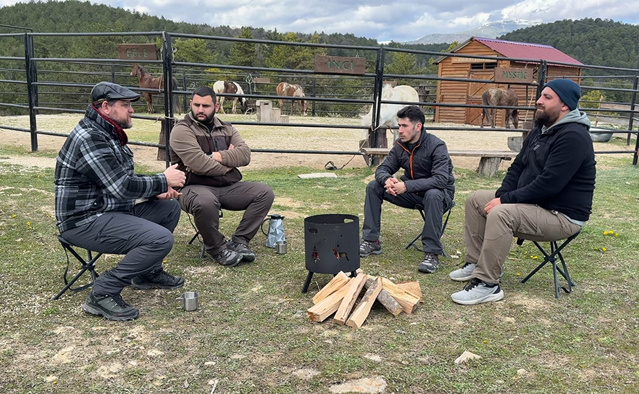 four men sitting around campfire