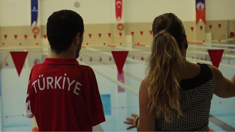 Beytullah and SAT-7 presenter looking out at pool.